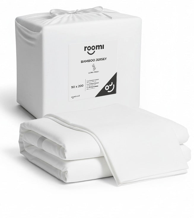חבילת חידוש מצעים לבנים מבית Roomi — כל מה שצריך למיטה שלכם, מלבד המזרן, מוצג באריזה השקופה של Roomi.