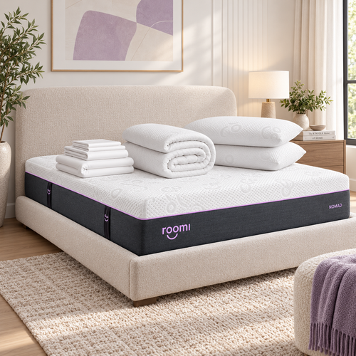 מיטה מסודרת עם “חבילת התמיכה Roomi Nomad” · הסט התומך, בחדר שינה נעים, מודרני ומואר היטב.