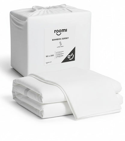 חבילת חידוש מצעים לבנים מבית Roomi — כל מה שצריך למיטה שלכם, מלבד המזרן, מוצג באריזה השקופה של Roomi.